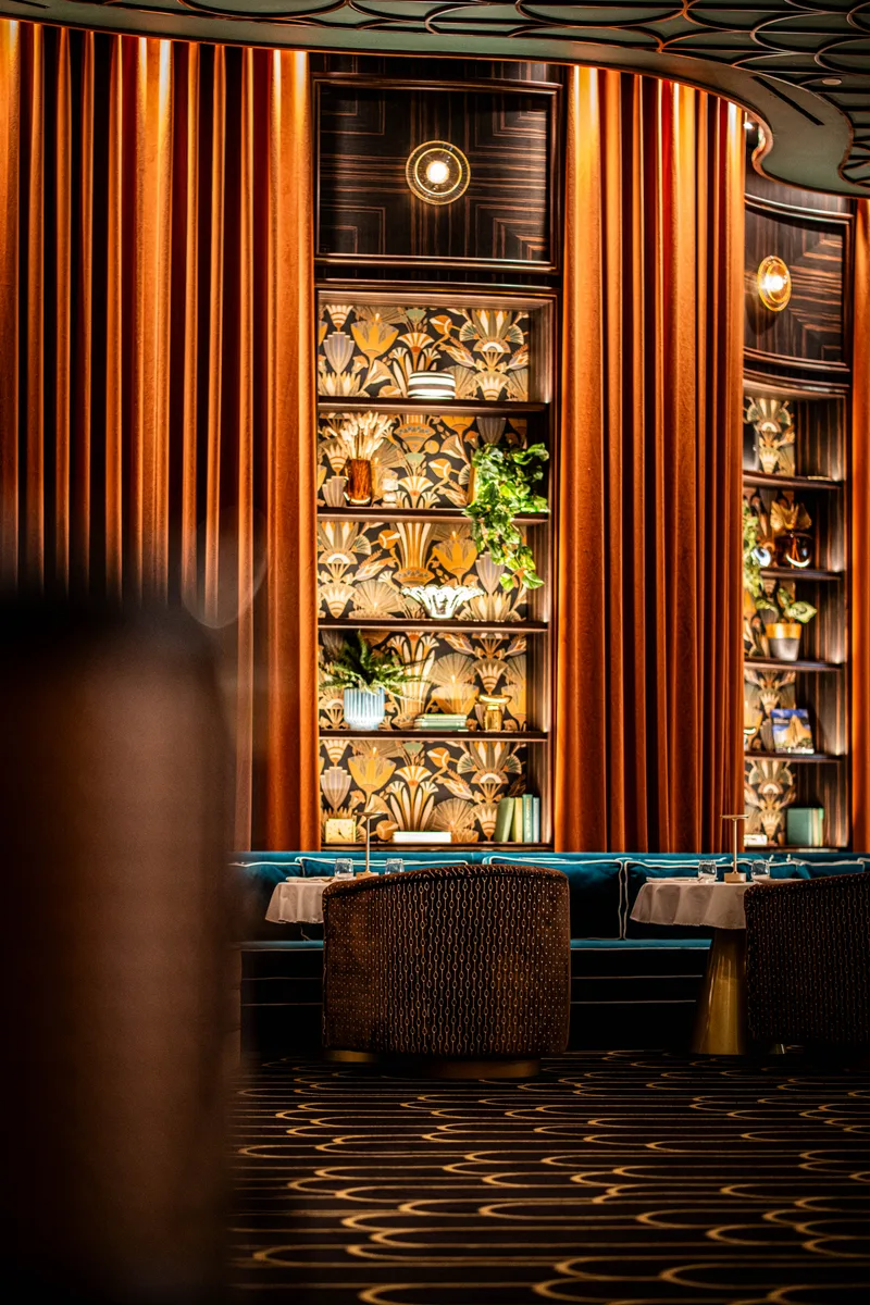 Decorative shelving and teal seating in a warmly lit lounge
