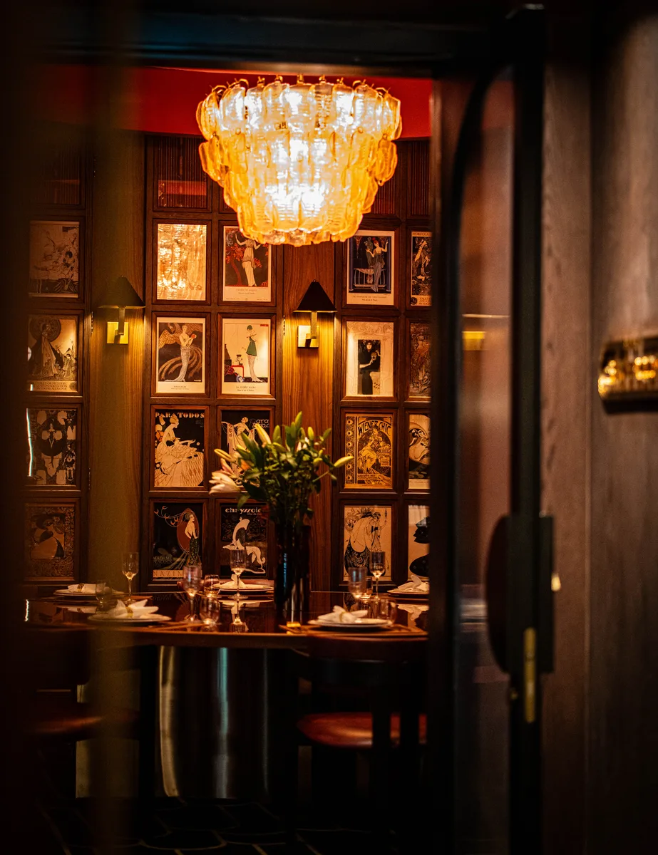 Amber chandelier above a dining room lined with framed artwork