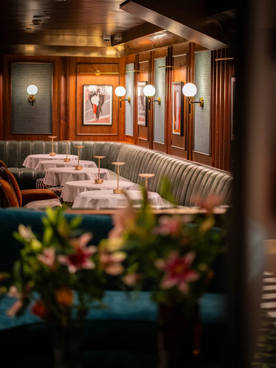 Dining tables and curved banquette beneath warm globe lights