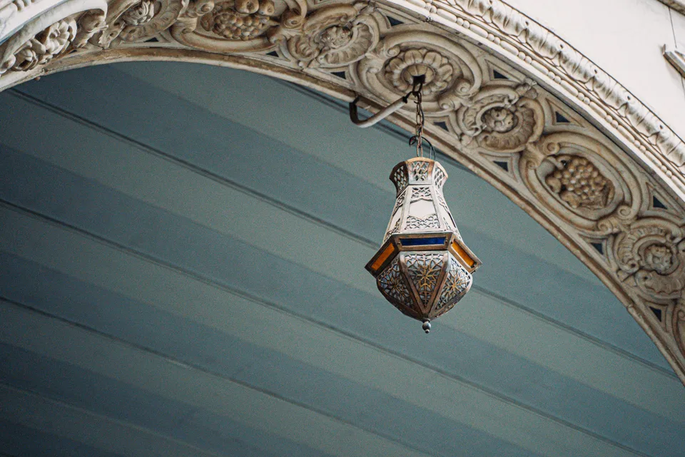 A patterned lantern beneath an ornate arch at Maktab Anbar