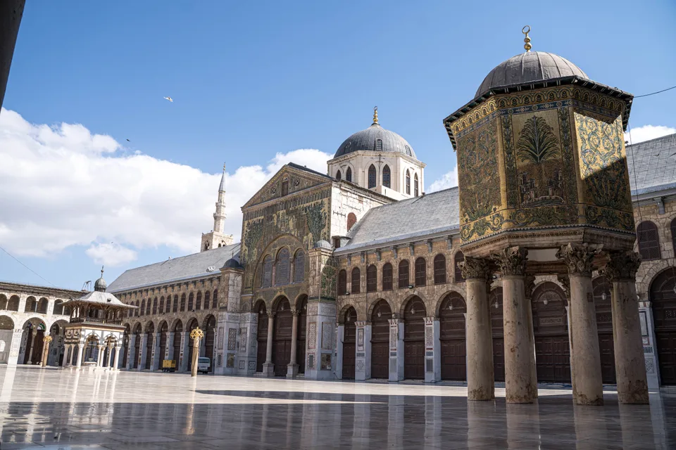 Umayyad Mosque courtyard with mosaic architecture beneath a blue sky