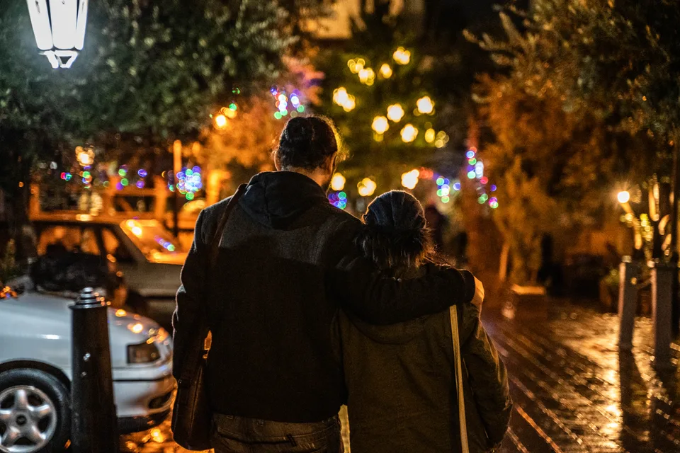 A couple walking beneath warm street lights at night