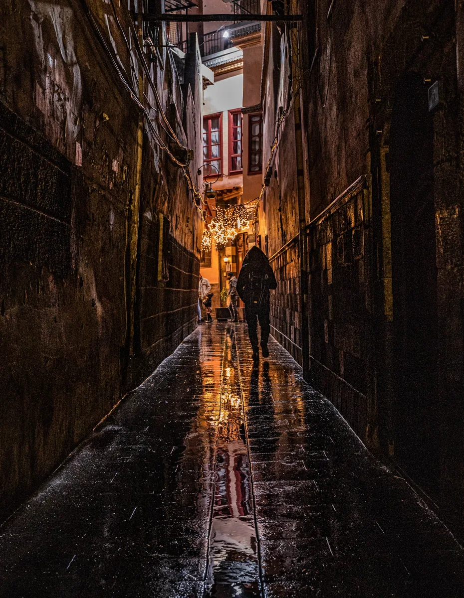 A figure walking through a rain-lit alley in Bab Sharqi